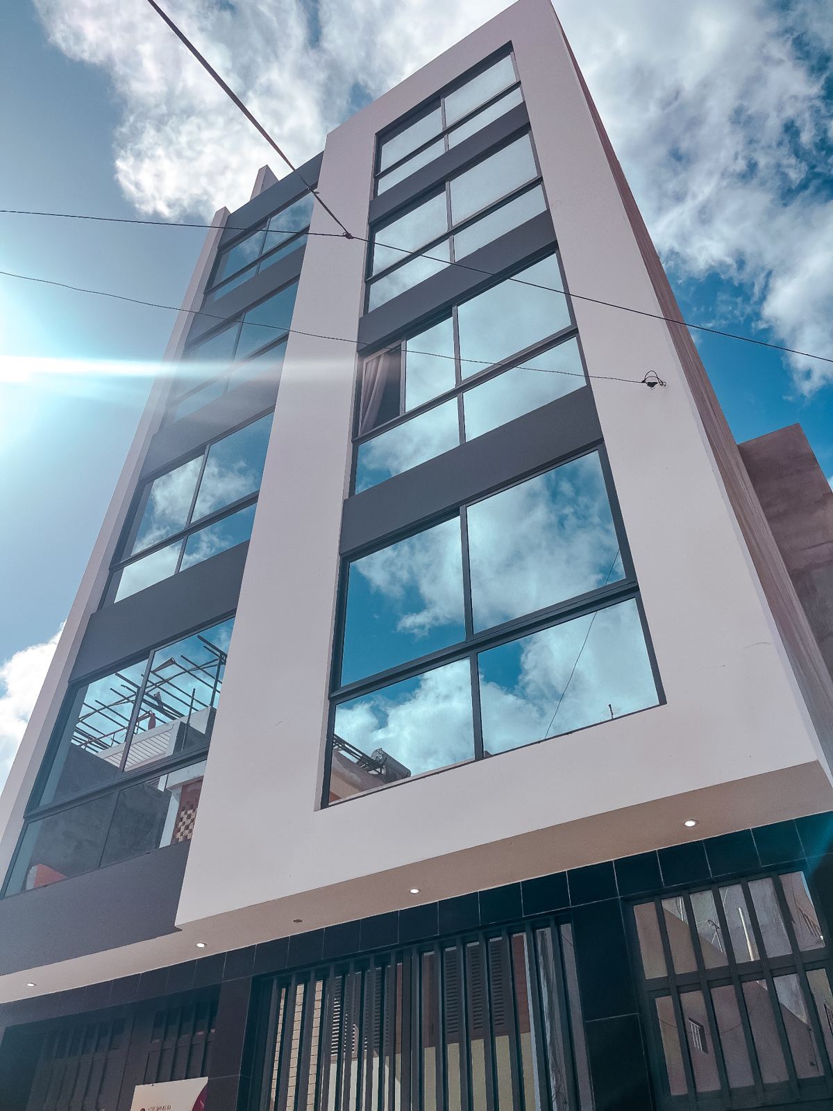 Modern appartementengebouw met grote glaspartijen tegen een blauwe hemel in Mindelo